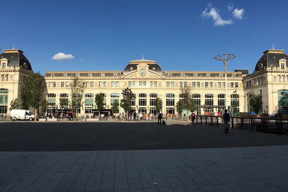 Parvis et façade de la gare Matabiau à Toulouse, voyageurs au loin