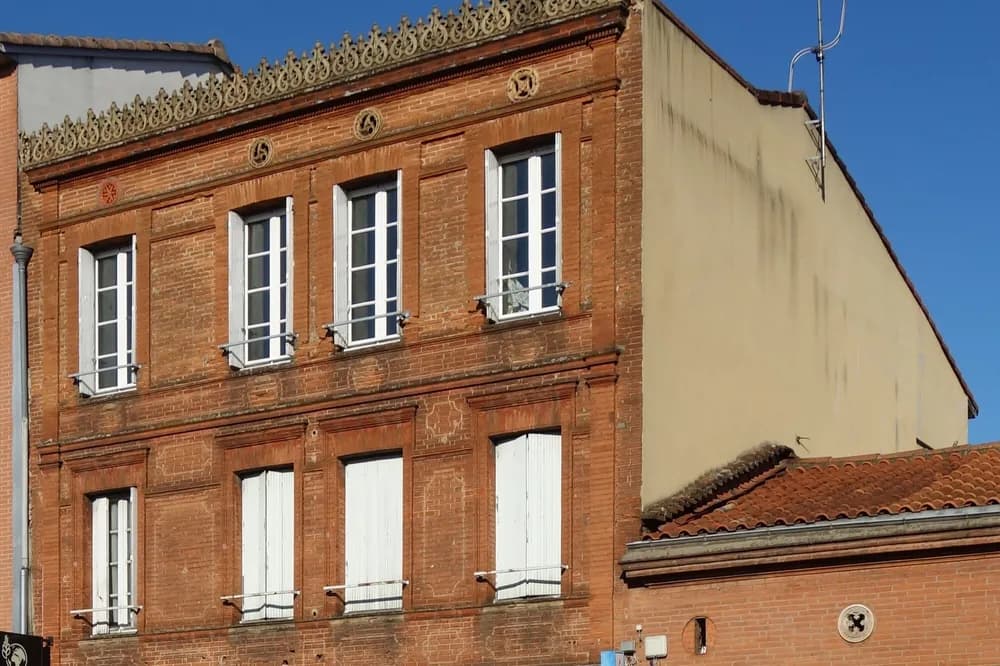 Façade de brique d'un immeuble ancien du faubourg Bonnefoy à Toulouse, volets clos
